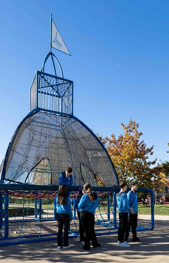 Tre ragazze e altrettanti ragazzi chiacchierano davanti alla struttura metallica azzurra a forma di cupola del campus di IST. Tutti indossano la divisa della scuola, con pantaloni blu navy e felpa azzurra