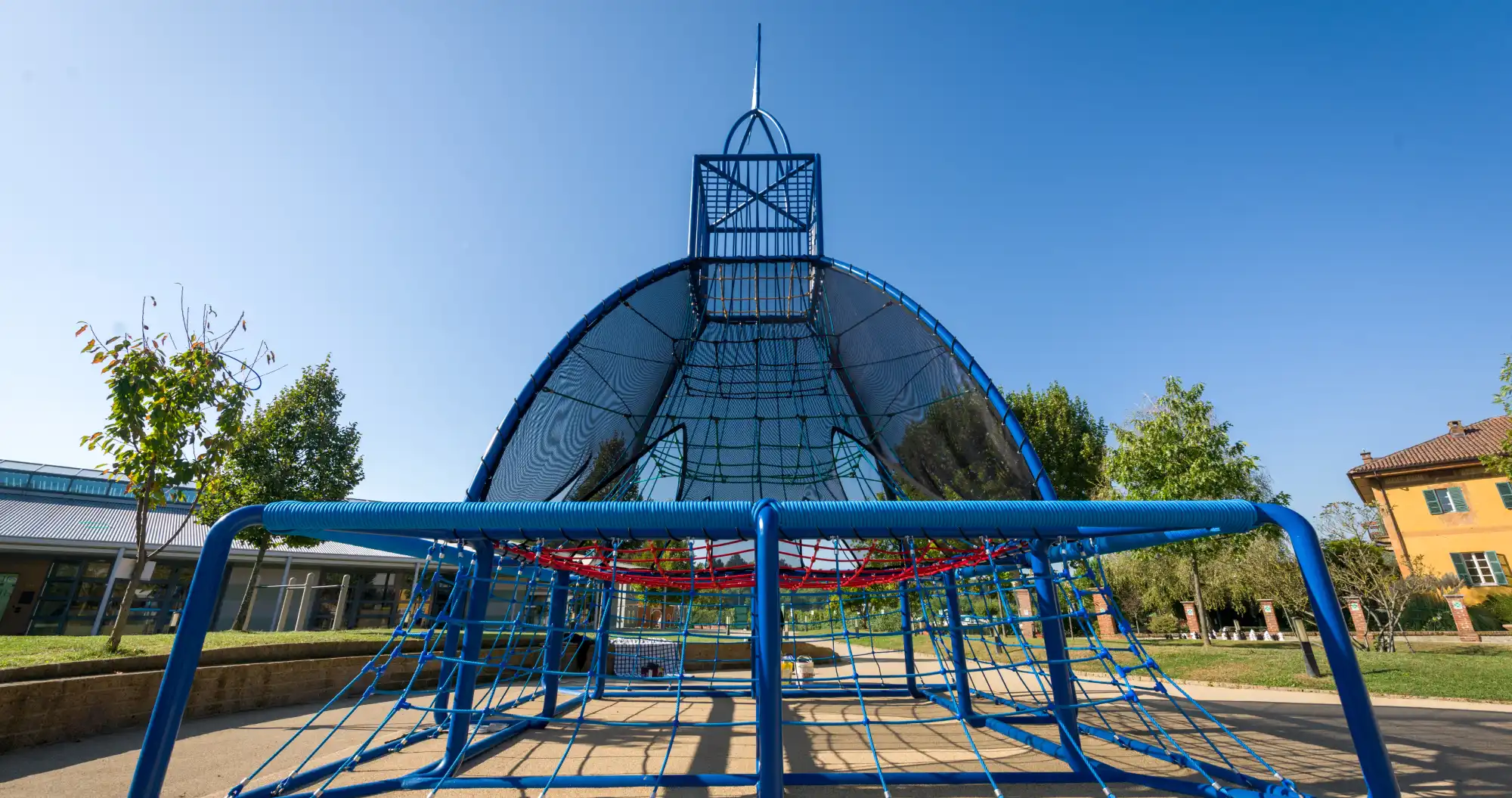 Struttura in tubi e rete di metallo azzurro a cupola nell’area giochi interna dell’ IST campus torino